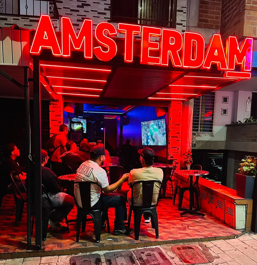 Fachada de Amsterdam Cocktails con su letrero de neón rojo en San Javier, Medellín